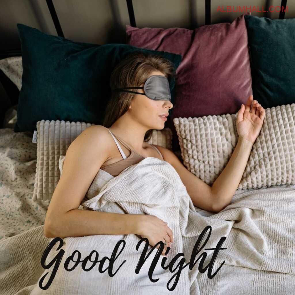 Girl with grey color eye blind and brown color hair sleeping on her bed with move and red color pillows around in the night