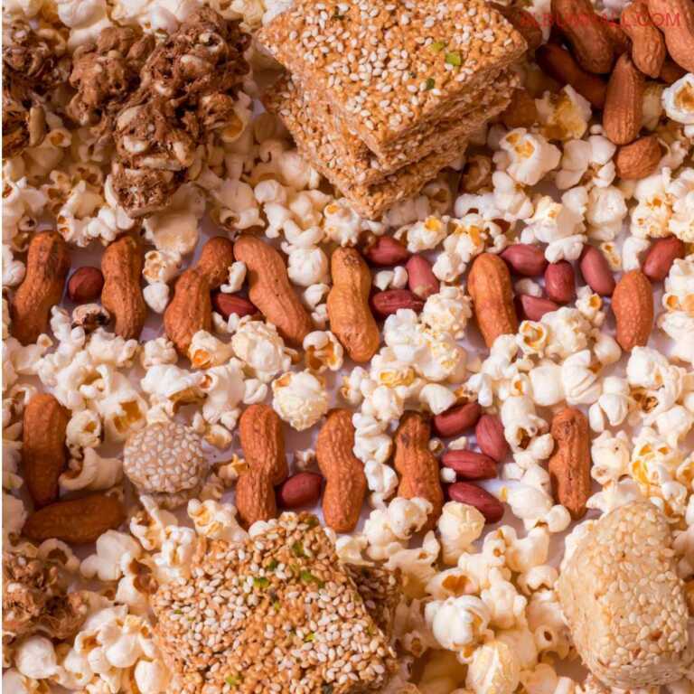 Jaggery sweets, popcorns and peanuts lying around saying Happy lohri written with sweets, pocorn and peanuts