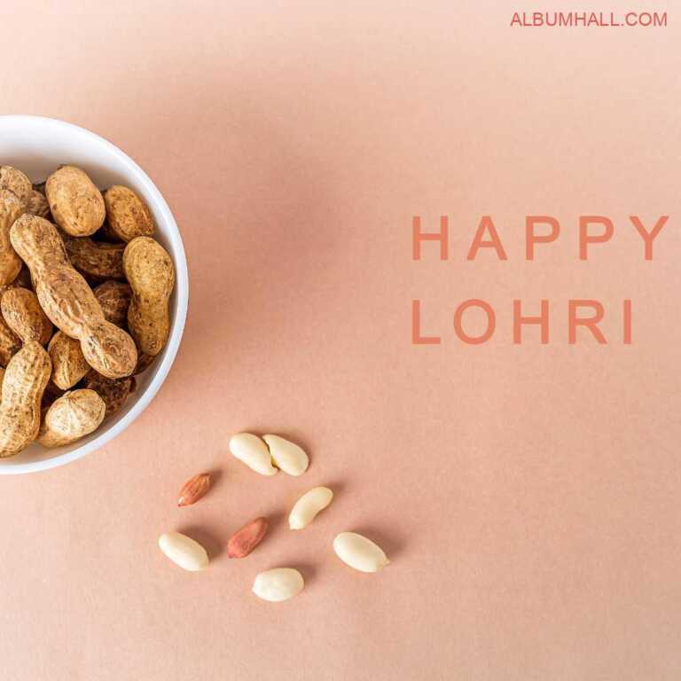 Half visible white bowl filled with raw peanuts and few of them lying on the pink color table for Lohri festival