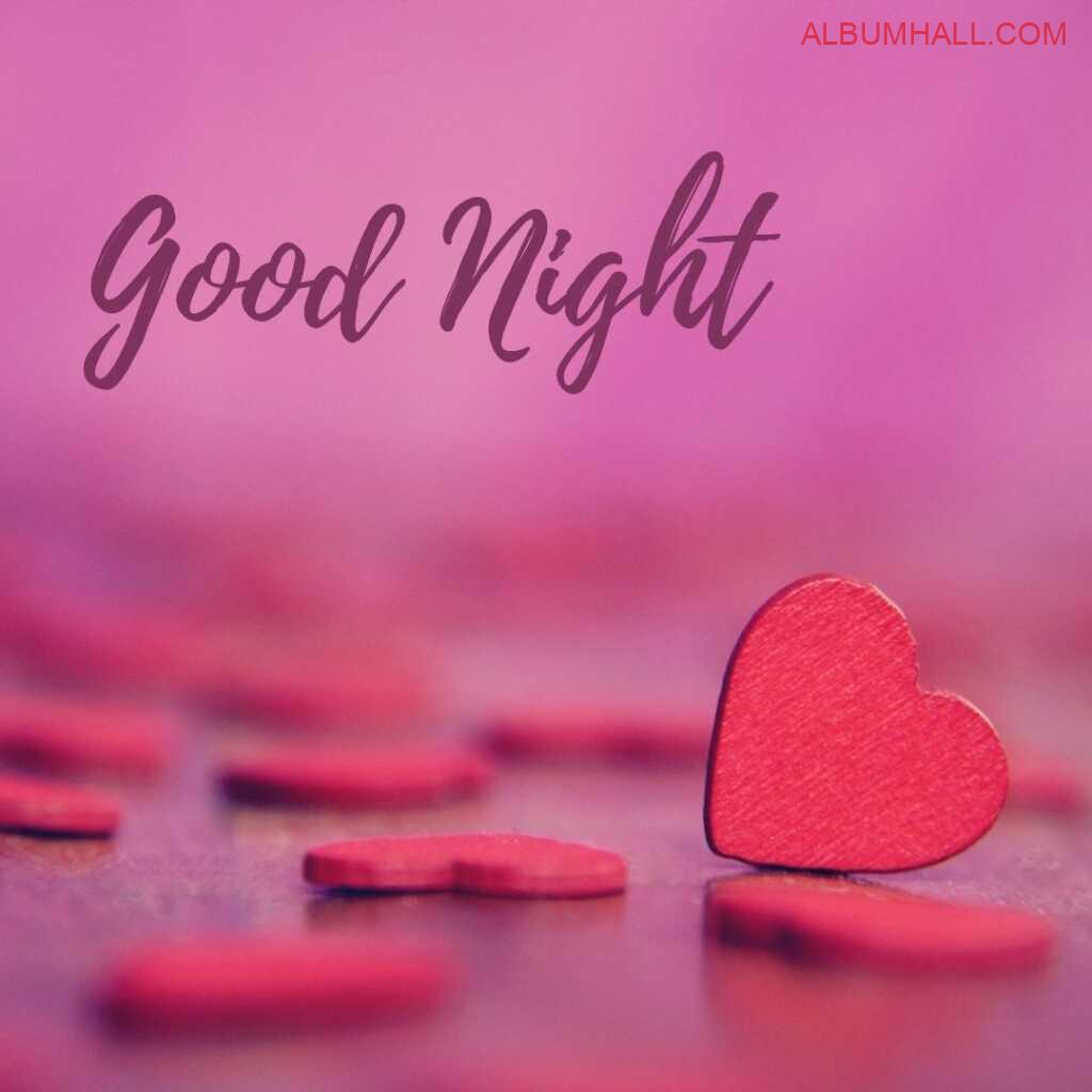 Red shaped tilted hearts lying on the table with light pink background wishing a very good night