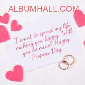 paper with pink hearts and two rings with propose day quotes saying "I want to spend my life making you happy. Will you be mine? Happy Propose Day."
